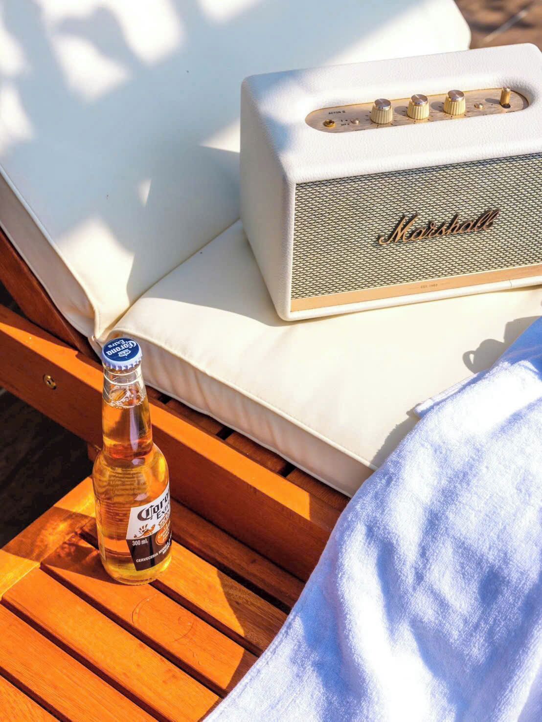 A lounge chair with a bottle of Corona beer and a Marshall amplifier on a wooden table.