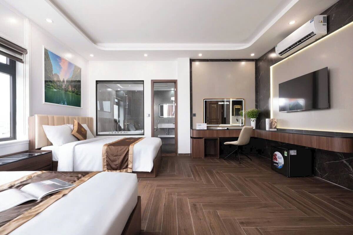 Una habitación de hotel moderna con dos camas, un escritorio, un televisor y un ventanal grande.