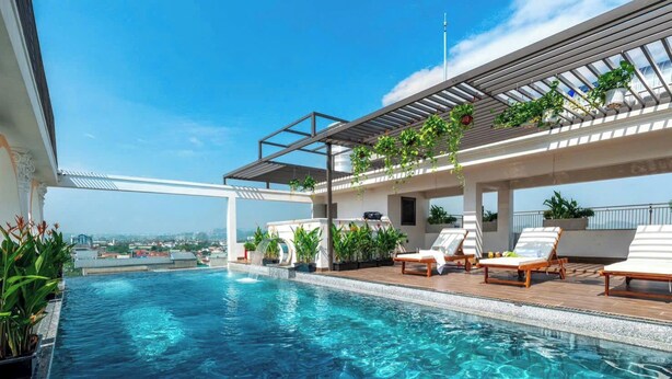 Una piscina infinita en la azotea con sillones de descanso y plantas en macetas.
