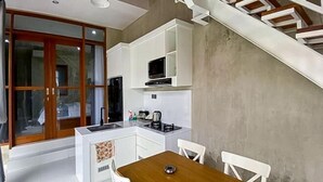 Une cuisine compacte avec un coin repas, des meubles blancs et un micro-ondes encastré.
