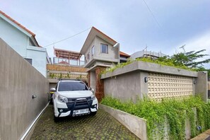 Un camino estrecho que lleva a una casa de dos pisos, con un coche estacionado en el centro.