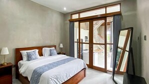 Une chambre avec un grand lit, une table de chevet, un miroir et une porte-fenêtre coulissante donnant sur un balcon.