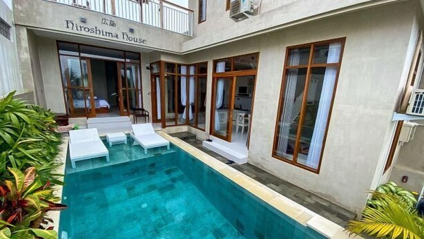 Une piscine avec des chaises longues, un patio couvert et un bâtiment portant l’inscription « Hiroshina House ».