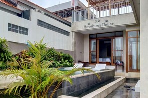 Ein modernes Gebäude mit der Aufschrift 'Hiroshima House'. Es verfügt über einen Poolbereich mit Liegestühlen und einem kleinen Wasserfall.