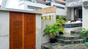 Un bâtiment moderne avec une porte en bois, des plantes en pot et une enseigne indiquant « Hôtel Niroshima ».