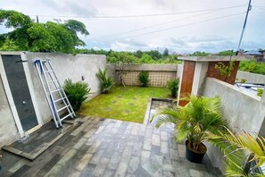 A small courtyard with a concrete wall, a ladder, and potted plants. - Hirosima House Bali by The Lavana (Bali)