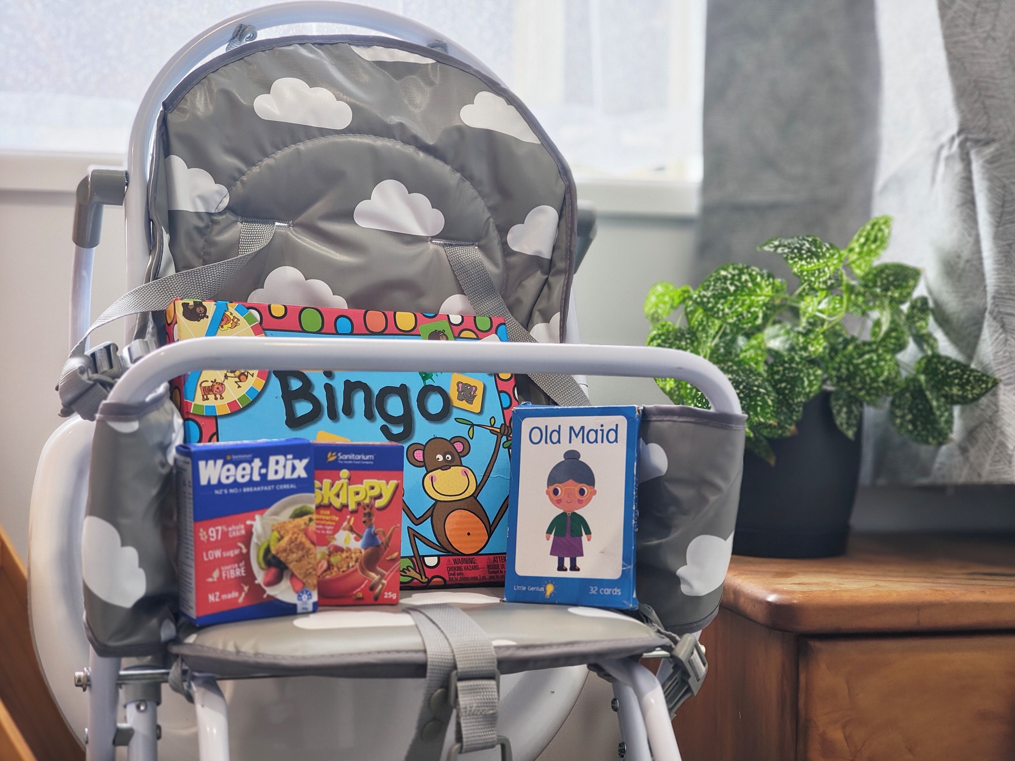 A baby stroller with a BINGO board, a box of Weet-Bix, a box of Skippy, and a book titled "Old Maid".