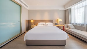 Een hotelkamer met een groot bed, een bank, een nachtkastje en een raam met gordijnen.