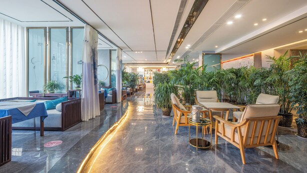 Een moderne hotel lobby met een pooltafel, een zithoek en volop kamerplanten.
