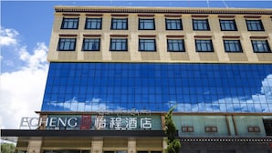 Een hotel met een moderne gevel, grote glasramen en een bord met tekst in zowel Engels als Chinees.