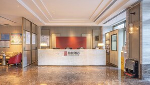 Een hotel receptie met een marmeren vloer, een receptiebalie en een rode accentmuur.