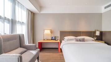 Una habitación de hotel con cama, escritorio, silla y mesita de noche con lámparas.
