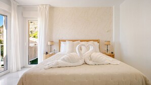 A hotel room with a bed, a nightstand, a lamp, and a view of the outdoors. - The Oasis Beachfront Villa (Almuñécar)