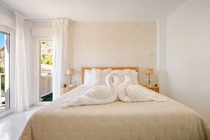 Ein Hotelzimmer mit Bett, Nachttisch, Lampe und Blick ins Freie.