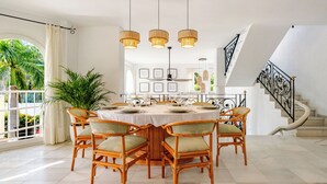 A dining area with a round table, six chairs, and hanging light fixtures. - The Oasis Beachfront Villa (Almuñécar)
