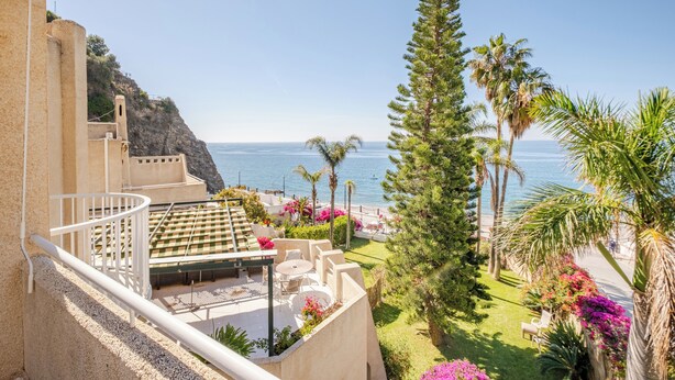 A balcony with outdoor seating, a view of the sea, and a garden with various plants. - The Oasis Beachfront Villa (Almuñécar)