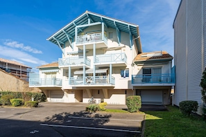 A multi-story residential building with balconies, a garage, and a parking area. - Cozy Apartment Between Beach and Harbor – Capbreton (Capbreton)