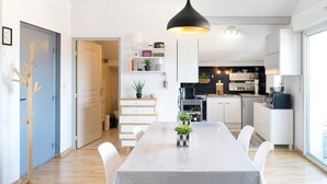 Une cuisine moderne avec des meubles blancs, un micro-ondes noir et un luminaire suspendu.