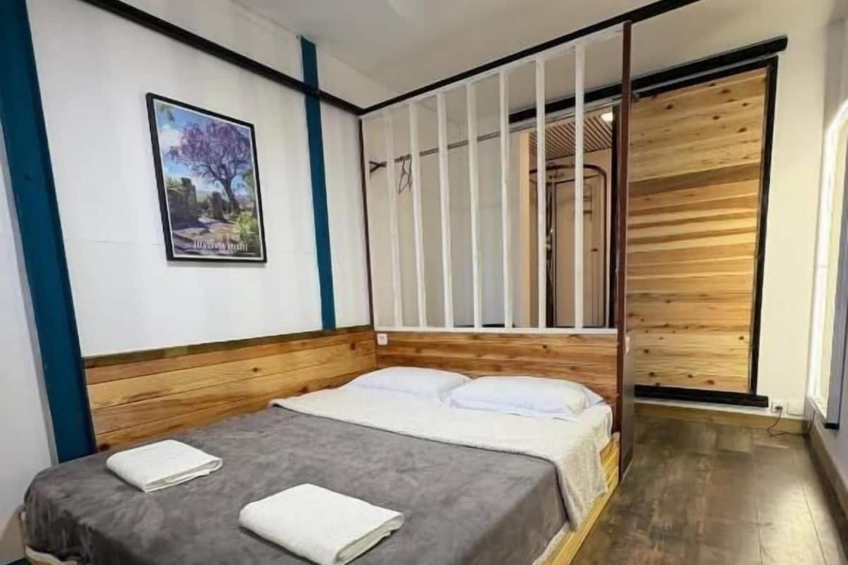 A bedroom with a wooden bed, a ceiling fan, a framed picture on the wall, and a sliding door.