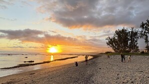 A beach at sunset with people walking and sitting on the sand. - Zébulon (Saint-Pierre)