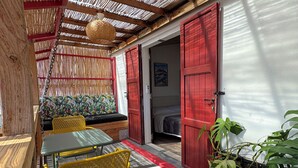 A covered outdoor seating area with a table and chairs, a door, and a plant. - Zébulon (Saint-Pierre)