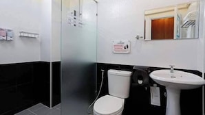 A bathroom with a white toilet, a glass shower enclosure, a sink, and a mirror. - The Vega Resort  (Bang Lamung)