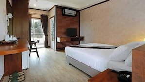 A hotel room with a bed, a desk with a chair, a television, and a window with curtains. - The Vega Resort  (Bang Lamung)