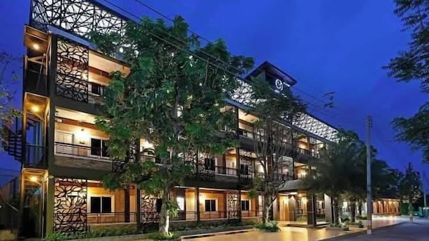 A multi-story hotel with a modern architectural design, featuring balconies and a well-lit exterior. - The Vega Resort  (Bang Lamung)