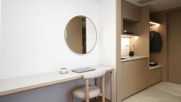 A modern, minimalist room with a white desk, a round mirror, a laptop, and a cup of coffee.