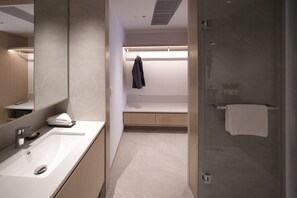 A modern bathroom with a large mirror, a sink, a shower, and a towel rack. - Stage Well Hotel (Kowloon)