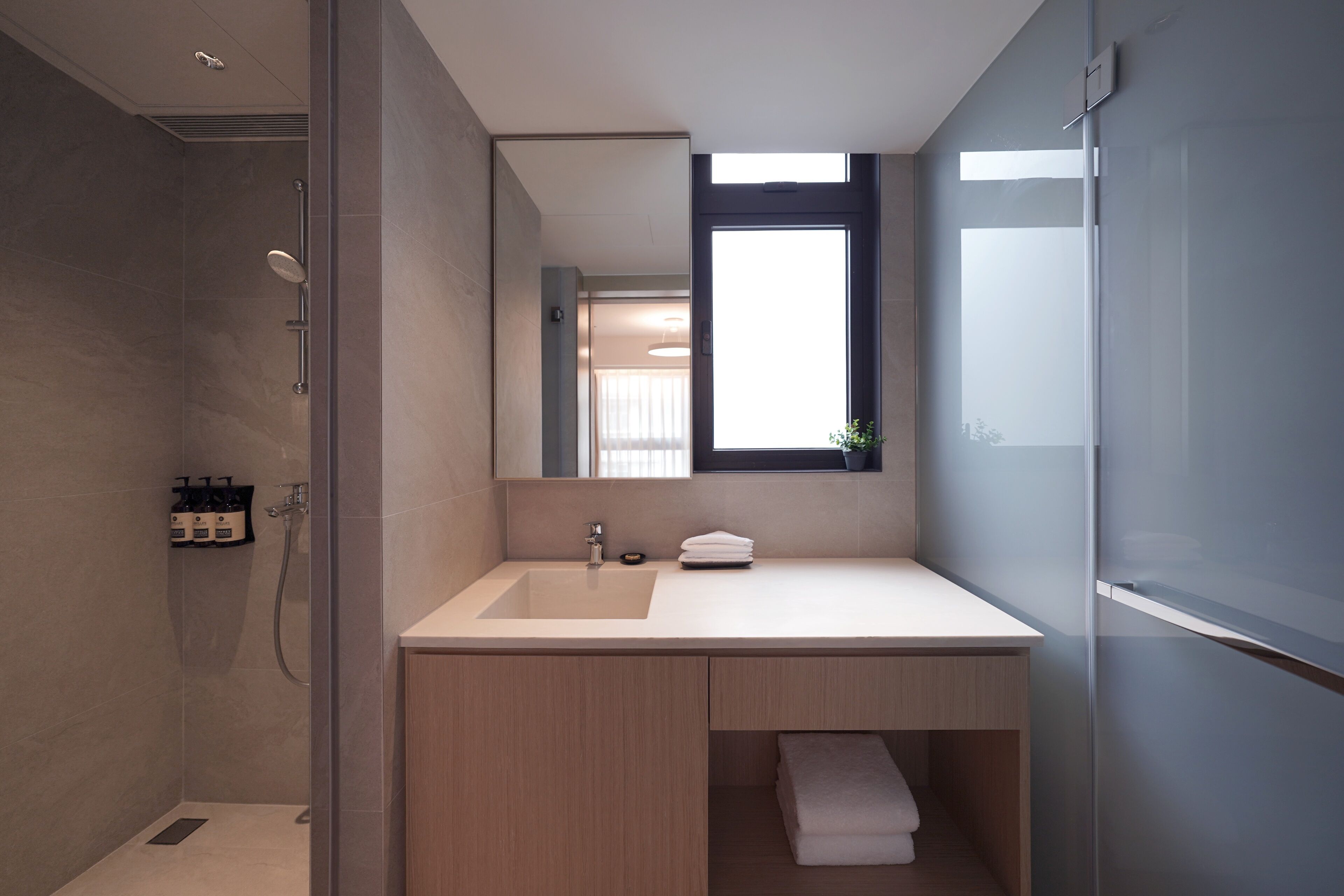 Une salle de bain moderne avec un grand miroir, un lavabo et une douche.