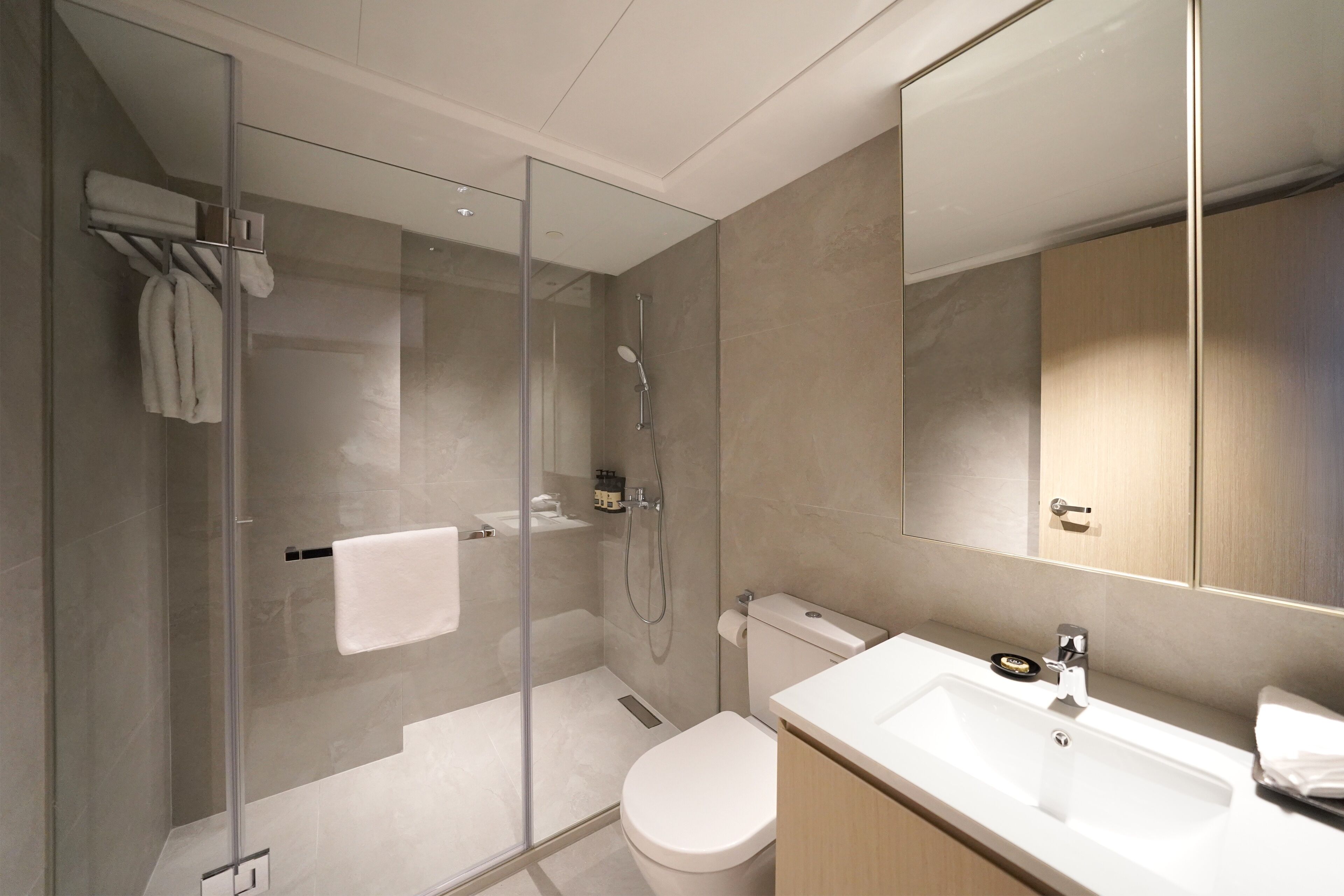 Un baño moderno con cabina de ducha de vidrio, inodoro y lavamanos con espejo.