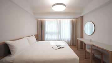 A modern hotel room with a large bed, a desk, and a round mirror.