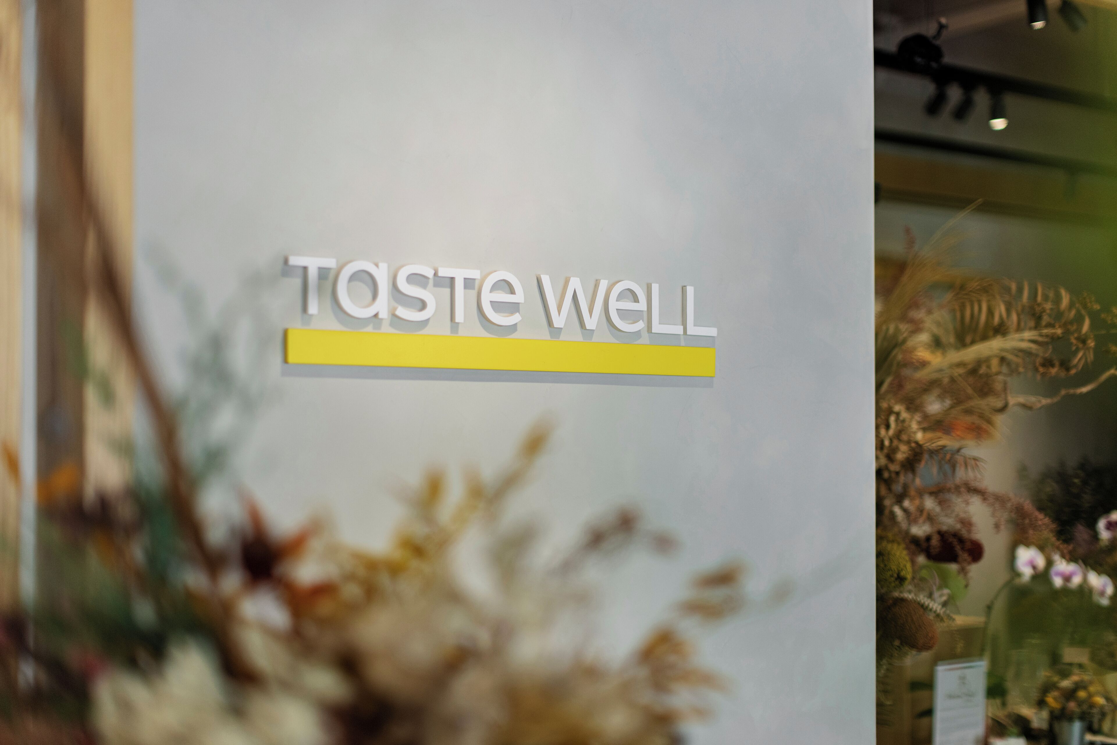 A sign with the text "TASTE WELL" and a horizontal line beneath it.
