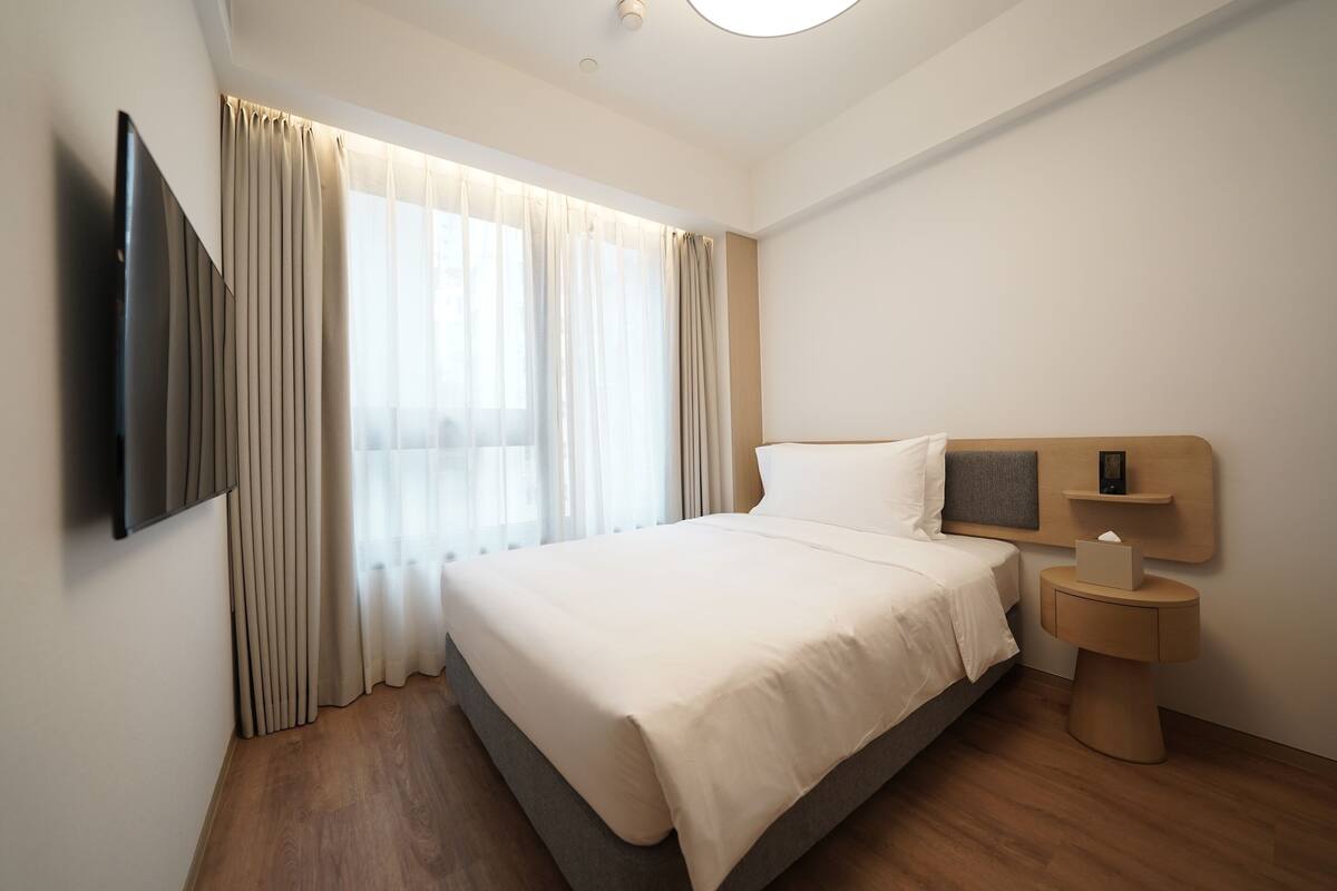 غرفة فردية - منظر للمدينة | ألحفة محشوة بالريش وخزنة داخل الغرفة ومكتب ومساحة عمل للكمبيوتر المحمول