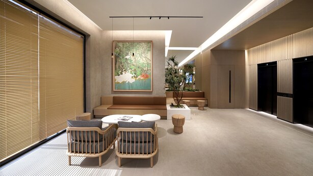 En moderne lobby med et siddeområde, et stort maleri og en potteplante.