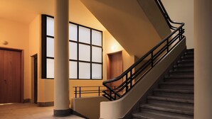 Un escalier avec une rampe, une porte en bois et une grande fenêtre à carreaux.