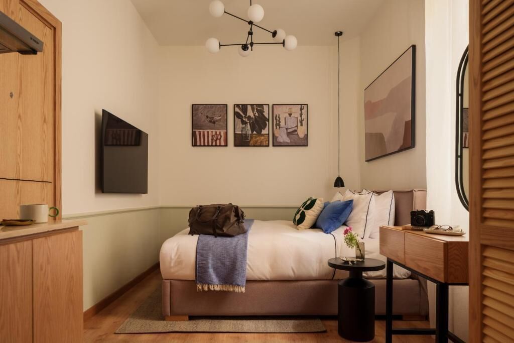 A bedroom with a bed, bedside table, and artwork on the wall.