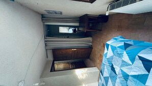 A compact room with a kitchenette, a small wooden cabinet, and a patterned bedspread. - Gîte 6 people 15min from Angers (Loire-Authion)