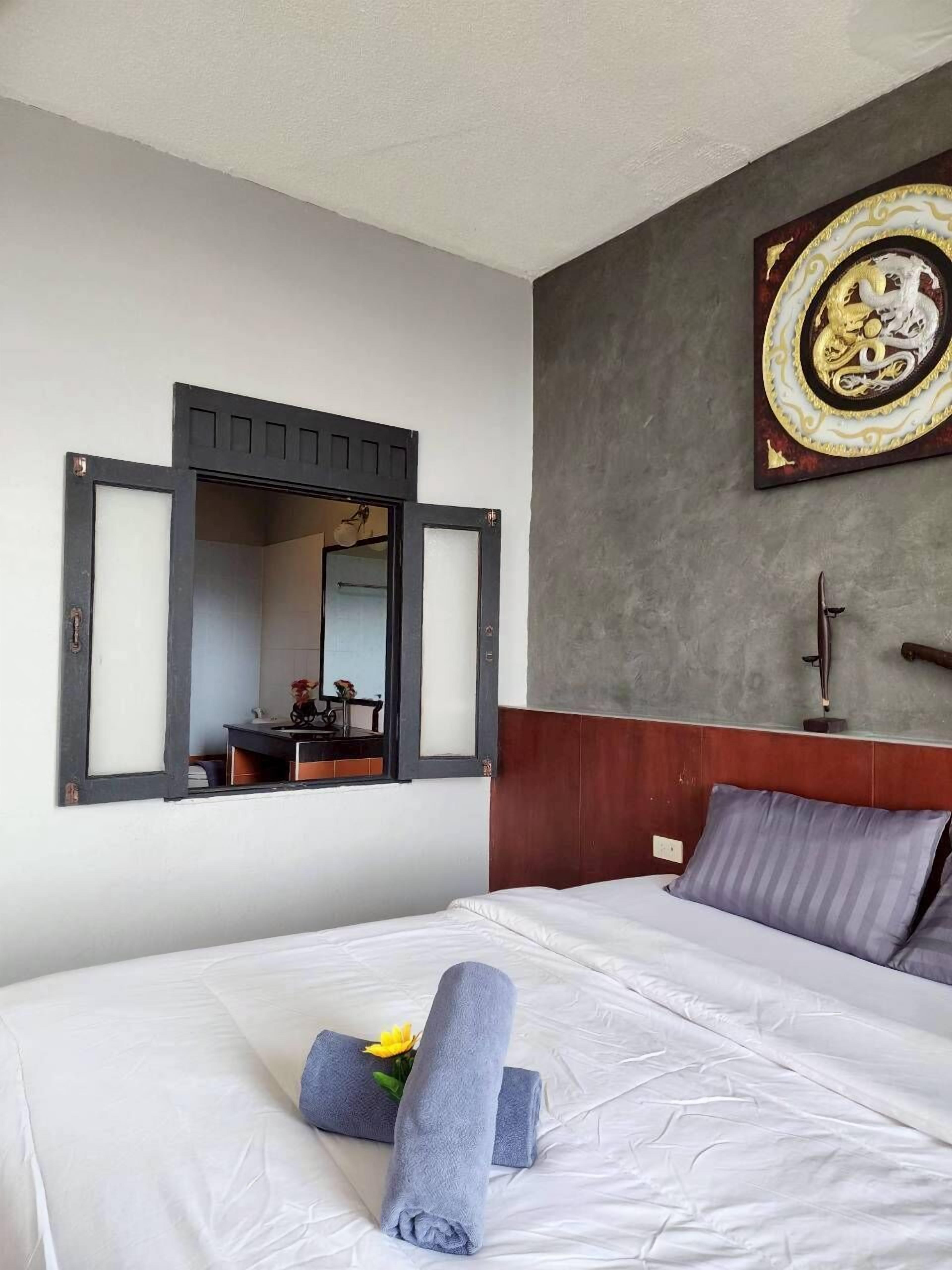 Habitación de hotel con cama, espejo adosado a la pared, decoración en la pared y ventana con vistas.