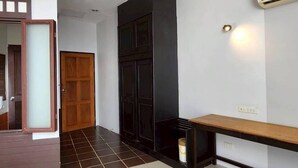 Um corredor com porta de madeira, armário preto e um banco.