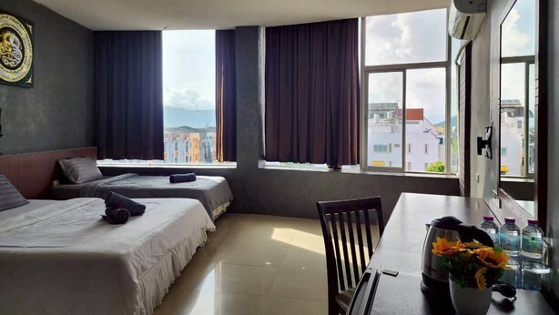 Quarto de hotel com duas camas, uma mesa de jantar e vista para a cidade.