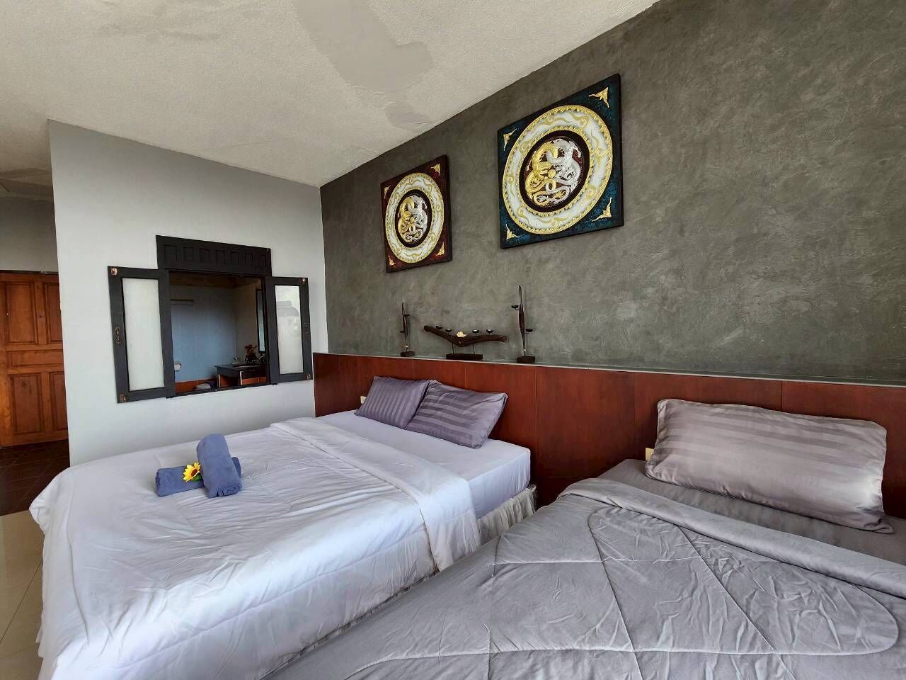 Quarto de hotel com duas camas, um espelho grande e duas peças decorativas na parede.