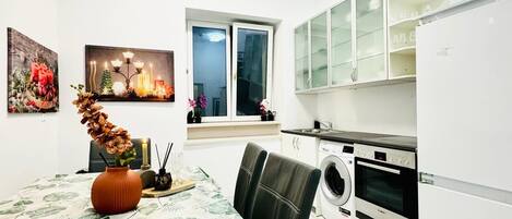 A modern kitchen with white cabinets, a built-in oven, and a window with a view.