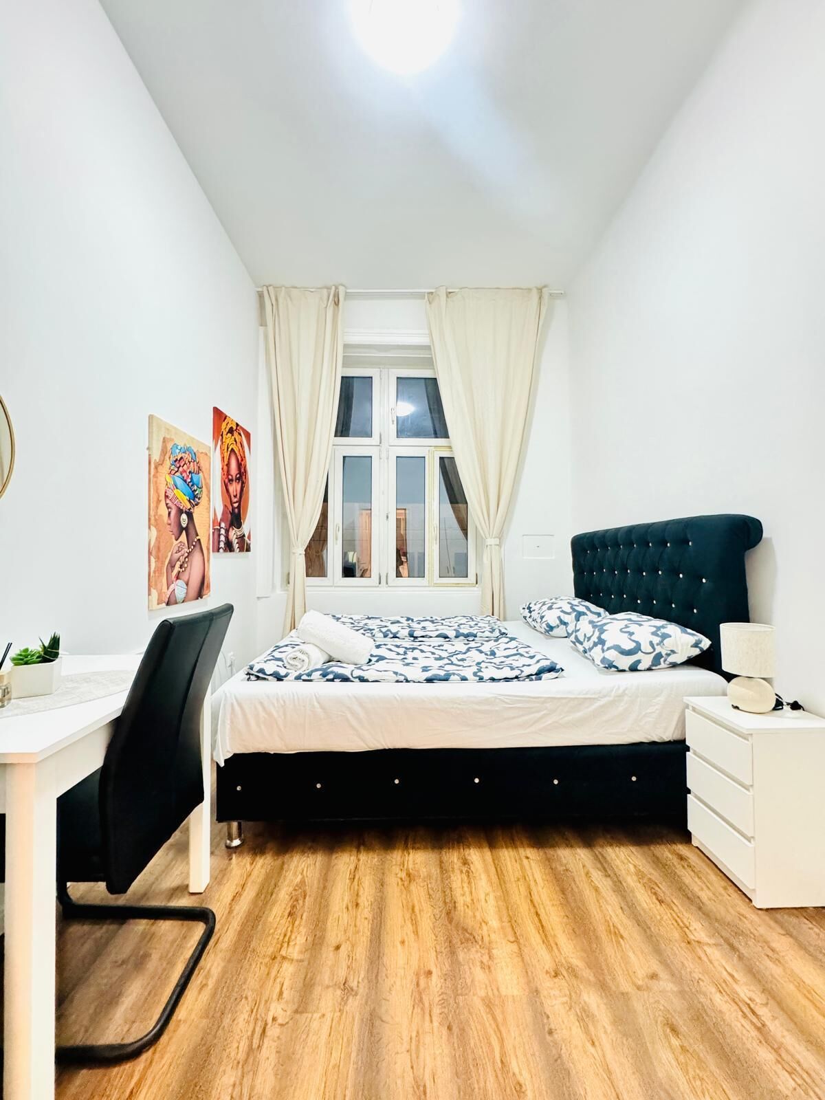 A bedroom with a bed, a desk, and a chair.