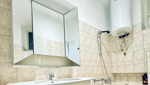 Un baño moderno con un espejo grande, un lavabo, una bañera y una ducha.
