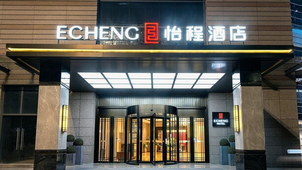 The entrance of the ECHENG Hotel with a modern design, featuring a glass revolving door and a signboard above the entrance. - yangjiangshibailiyichengjiudian  (Yangjiang)