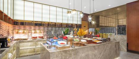 A modern buffet setup with a marble counter, various food items, and a brick wall backdrop.