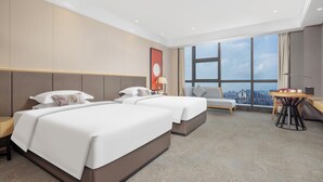 A hotel room with two beds, a desk, and a view of the city. - yangjiangshibailiyichengjiudian  (Yangjiang)