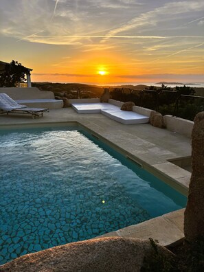 A pool area with a sunset view, including a sun lounger and seating area. - DomoMea Porto Cervo (Arzachena)